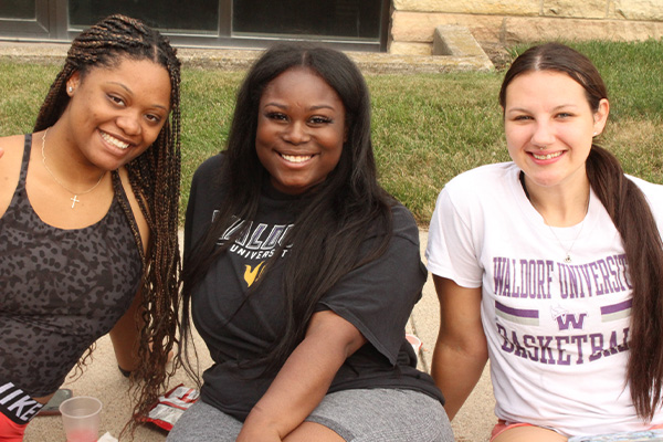 Close up of diverse females sitting on the curb smiling at camera 